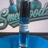 A small glass roll-on bottle with blue liquid and a black cap stands on a reflective blue circular platform. The bottle label reads 'Fragrances'